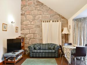 een woonkamer met een bank en een tafel bij Pine Tree Cottage - Uk45925 in Ballater