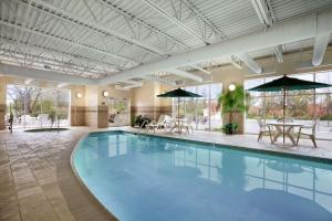 una gran piscina con mesas y sombrillas en un edificio en Country Inn & Suites by Radisson, State College Penn State Area , PA, en State College