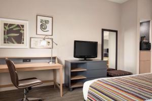 Habitación de hotel con cama, escritorio y TV. en Country Inn & Suites by Radisson, Florence, SC, en Florence