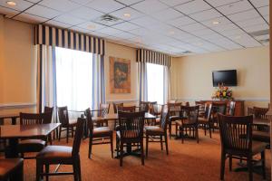 a restaurant with tables and chairs and a flat screen tv at Country Inn & Suites by Radisson, Orangeburg, SC in Orangeburg
