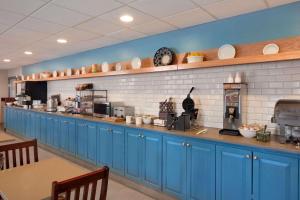 a kitchen with blue cabinets and plates on the wall at Country Inn & Suites by Radisson, Aiken, SC in Aiken