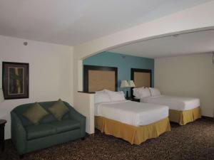 Country Inn & Suites by Radisson, Murrells Inlet, SC في ميرتل بيتش: غرفة فندقية بسريرين واريكة خضراء