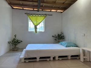 a bed in a white room with a window at Punta Arena EcoHostal & EcoFit 03 in Playa Punta Arena
