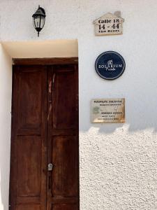 une porte en bois et un panneau sur un mur blanc dans l'établissement Hotel Solárium Posada, à Socorro