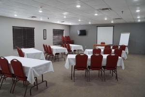 a conference room with white tables and red chairs at Country Inn & Suites by Radisson, Watertown, SD in Watertown