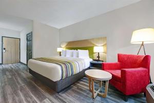 a hotel room with a bed and a red chair at Country Inn & Suites by Radisson, Pierre, SD in Pierre
