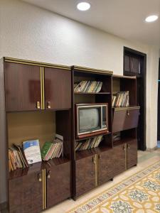 a room with two shelves with a microwave and a tv at Roman Theater Hotel in Amman