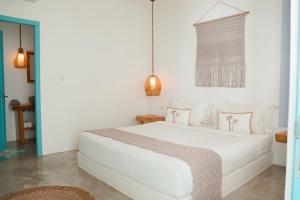 a white bedroom with a white bed with pink pillows at Seaesta Komodo Hostel & Hotel in Labuan Bajo