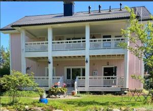 a large pink house with a large porch at Wanha Neuvola Guesthouse in Pieksämäki