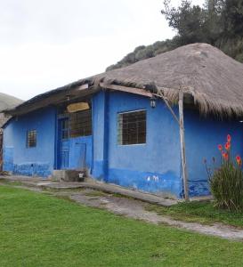 una casa azul con techo de paja en Hacienda Yanahurco en Ovejería