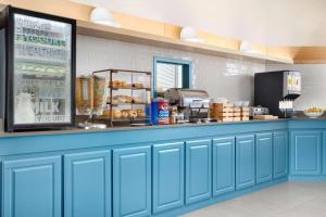 a kitchen with blue cabinets and a counter with food at Country Inn & Suites by Radisson, Fort Worth West l-30 NAS JRB in Fort Worth