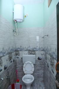 a bathroom with a toilet with a painting on the wall at Thulir in Vālpārai