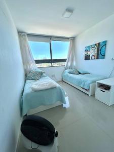 a bedroom with two beds and a window at Apartamento en Edificio Chronos in Punta del Este +13 photos