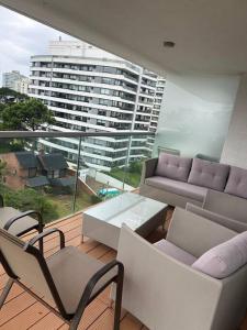 a balcony with a couch and chairs and a table at Apartamento en Edificio Chronos in Punta del Este