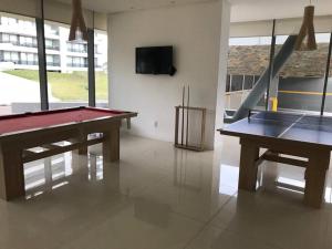 a room with two ping pong tables and a tv at Apartamento en Edificio Chronos in Punta del Este