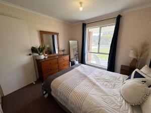 a bedroom with a bed with a dresser and a window at The J's - Pets welcome outside in Robe