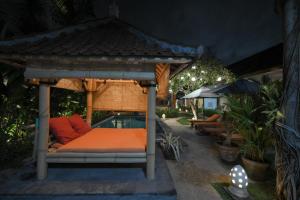 a bed in a gazebo in a garden at night at Tiga Naga Villa in Denpasar