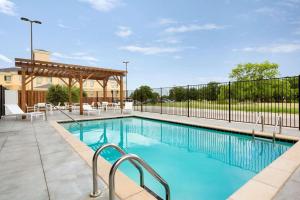 einen Pool mit Stühlen und einem Zaun in der Unterkunft Country Inn & Suites by Radisson, New Braunfels, TX in New Braunfels