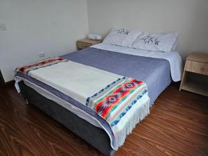 Una cama con una manta de colores en un dormitorio en centro de pasto apartamento kz, en Pasto