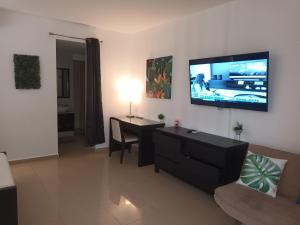 a living room with a table and a tv on the wall at Playa Blanca Panama in Río Hato