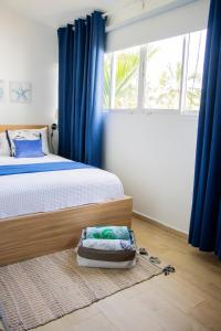 a bedroom with a bed with blue curtains and a window at EL Bonito II Juan Dolio DR 2 room sleeps6 1queen bed 2twin bed 1sofa bed in Juan Dolio