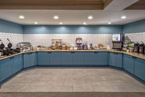 duża kuchnia z niebieskimi szafkami i ścianami wyłożonymi kafelkami w obiekcie Country Inn & Suites by Radisson, Potomac Mills Woodbridge, VA w mieście Woodbridge