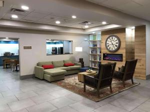 ein Wohnzimmer mit einem Sofa und einer Uhr an der Wand in der Unterkunft Country Inn & Suites by Radisson, Emporia, VA in Emporia