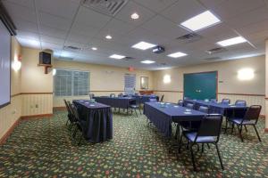 einen Konferenzraum mit blauen Tischen und Stühlen sowie einem Bildschirm in der Unterkunft Country Inn & Suites by Radisson, Winchester, VA in Winchester