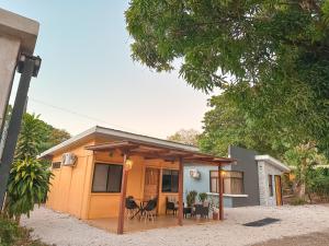 una pequeña casa amarilla con porche y patio en Casa CAXTUS, en Brasilito