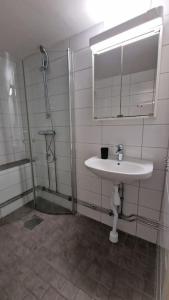 a bathroom with a sink and a shower and a mirror at Mysigt Stadsoas: En Modern lägenhet med 2 sovrum in Gothenburg