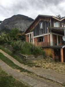 uma casa numa colina com uma montanha ao fundo em Casa Cerro Divisadero em Coihaique
