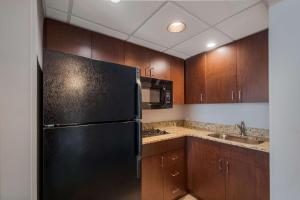 a kitchen with a black refrigerator and wooden cabinets at Country Inn & Suites by Radisson, Fredericksburg South I-95 , VA in Fredericksburg