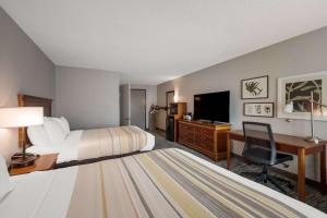 a hotel room with two beds and a desk and a television at Country Inn & Suites by Radisson, Fredericksburg South I-95 , VA in Fredericksburg