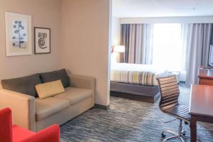 a hotel room with a couch and a bed at Country Inn & Suites by Radisson, Washington Dulles International Airport, VA in Sterling