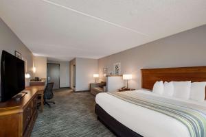 a hotel room with a bed and a flat screen tv at Country Inn & Suites by Radisson, Fredericksburg South I-95 , VA in Fredericksburg