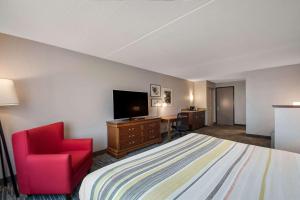 a hotel room with a bed and a chair and a television at Country Inn & Suites by Radisson, Fredericksburg South I-95 , VA in Fredericksburg