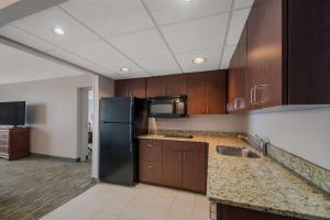 a kitchen with a black refrigerator and wooden cabinets at Country Inn & Suites by Radisson, Fredericksburg South I-95 , VA in Fredericksburg