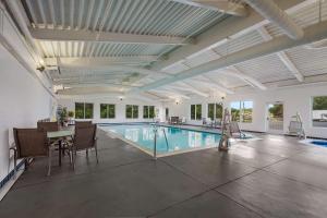 a swimming pool with a table and chairs in a building at Country Inn & Suites by Radisson, Fredericksburg South I-95 , VA in Fredericksburg