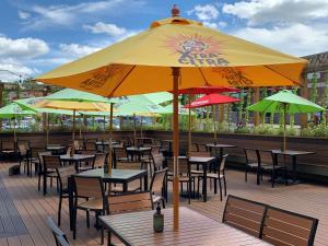 Radisson Hotel River Falls في River Falls: فناء به طاولات وكراسي تحت مظلة صفراء كبيرة