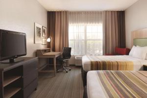 Habitación de hotel con 2 camas, escritorio y TV. en Country Inn & Suites by Radisson, Madison Southwest, WI, en Fitchburg