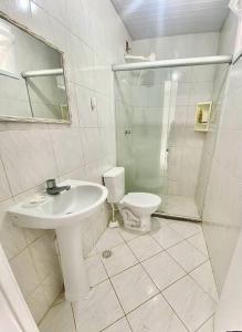 a white bathroom with a sink and a toilet at Casa em Praia do Flamengo - Salvador in Salvador