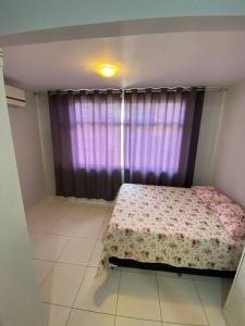 een slaapkamer met een bed voor een raam bij Casa em Praia do Flamengo - Salvador in Salvador