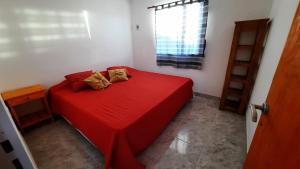 1 dormitorio con 1 cama roja y 2 almohadas en Cabañas Millaray en 