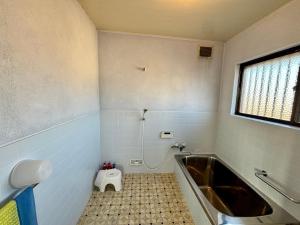 a bathroom with a tub and a toilet in it at 城跡石垣上の絶景古民家宿 鞆城茶屋庵 in Tomo