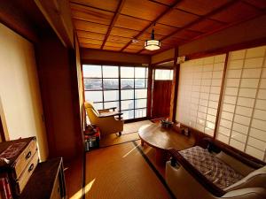 Tomo城跡石垣上の絶景古民家宿 鞆城茶屋庵的一间客房内配有桌子和沙发的房间