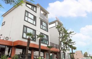 a white building with palm trees in front of it at Starlight drops Pension in Jeju