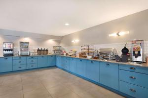 a large kitchen with blue cabinets and appliances at Country Inn & Suites by Radisson, Chippewa Falls, WI in Chippewa Falls