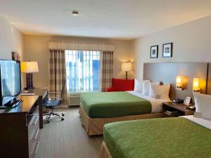 ケノーシャにあるCountry Inn & Suites by Radisson Kenosha - Pleasant Prairieのベッド2台とテレビが備わるホテルルームです。