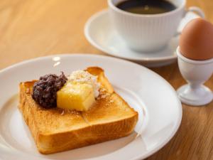 名古屋市にあるホテル・アンドルームス名古屋伏見のチーズをのせたトーストとコーヒーが入った白い皿