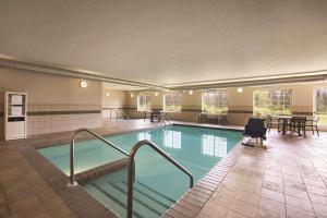 una gran piscina con una silla y mesas en Country Inn & Suites by Radisson, Green Bay North, WI, en Green Bay